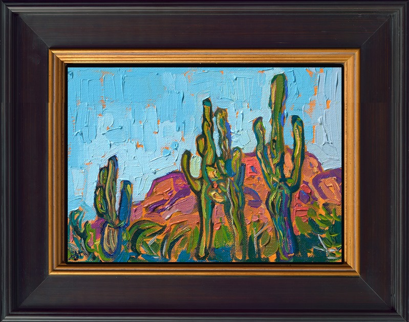 A petite work captures the beauty of Arizona with thick, expressive brush strokes of oil paint. Stately saguaros stand tall before a red rock boulder. This piece was created on linen board and arrives framed and ready to hang.
