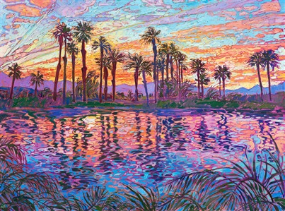 A brilliant rainbow of color bursts over Lake La Quinta, in the Coachella Valley. The desert palm trees stand starkly against the vibrant hues of dawn, reflected again in the still waters of the lake.